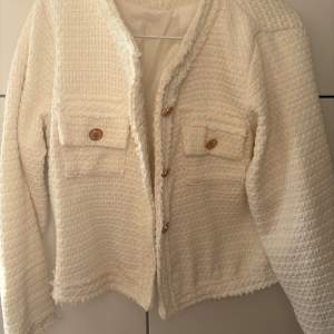 Säljer en stilren vit kavaj med textur och dekorativa knappar framtill. Påminner om Blair Waldorfs stil! Perfekt för en elegant look. Passar XS och S. Aldrig använd 