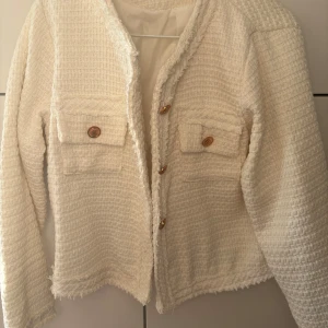 Vit tweed kavaj / kofta med knappar - Säljer en stilren vit kavaj med textur och dekorativa knappar framtill. Påminner om Blair Waldorfs stil! Perfekt för en elegant look. Passar XS och S. Aldrig använd 