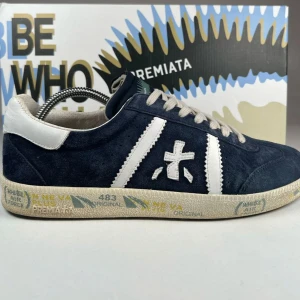 Blå sneakers från Premiata 42-43 - Snygga blå sneakers från Premiata i mocka med vita detaljer och snörning. Skorna har en unik design med märkets logga på sidan och en mönstrad sula. Perfekta för en stilren look. Passar både 42-43. Kom privat vid minsta funderingar!😴👊