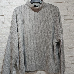 Grå ribbad tröja från Amisu - Säljer en stilren grå ribbad tröja från Amisu. Tröjan har en hög krage och långa ärmar, perfekt för kyligare dagar. Den är tillverkad i ett mjukt material som ger en bekväm passform. Passar utmärkt till både jeans och kjol. Hör av dig vid intresse!
