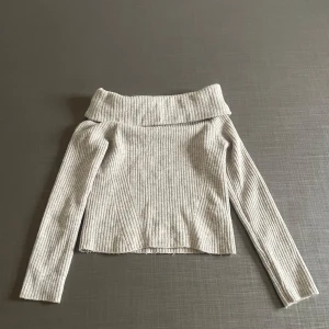 Grå ribbad offshoulder tröja - Snygg grå ribbad offshoulder tröja med långa ärmar.  Den mjuka och stretchiga designen gör den bekväm att bära hela dagen.