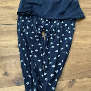 Mörkblå mjukisbyxor med stjärnor - Supermysiga mörkblå mjukisbyxor med vita stjärnor över hela. Perfekta för chill hemma eller när du vill vara extra bekväm. Byxorna har en loose passform och är gjorda i mjukt bomullstyg.