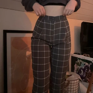 Grå rutiga högmidjade kostymbyxor - Snygga grå kostymbyxor med vitt rutmönster och hög midja. Byxorna har resår baktill i midjan för extra komfort. För korta i benen för mig