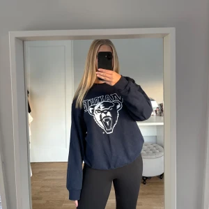 Mörkblå college-tröja med tryck - College-tröja i mörkblå med stort vitt tryck på bröstet. Klassisk rund halsringning och långa ärmar. Storlek M.