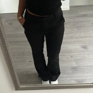 Svarta kostymbyxor med bootcut - Snygga svarta kostymbyxor med bootcut-snitt och normal passform. Byxorna har klassisk midja och raka ben som smalnar av lätt nedtill. (Spegeln är smutsig, inte byxorna). Mid waist 