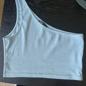 Ljusblå ribbad oneshoulder topp  - Snygg ljusblå ribbad topp från SHEIN med oneshoulder-design. Croppad modell. Storlek s 