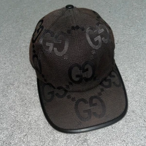 Gucci jumbo keps  - Snygg svart keps från Gucci med ikoniskt GG-mönster över hela kepsen. Kepsen har böjd skärm med svart kant och justerbar rem baktill. Tillverkad i slitstark polyester med exklusiv känsla, perfekt för dig som vill sticka ut med en lyxig accessoar.  ❌ÄKTA!!!❌