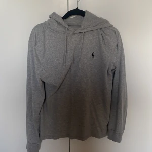 Grå hoodie från Polo Ralph Lauren - Snygg grå hoodie från Polo Ralph lauren. Lite tunnare material mycket skön hoodie och stilren.