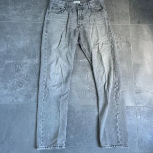 Grå loose fit jeans Jack & Jones - Säljer ett par grå jeans från Jack & Jones i loose fit-modellen Chris. Jeansen har klassisk femficksdesign, raka ben och är tillverkade i bomull. Perfekta för dig som gillar en avslappnad och trendig look.