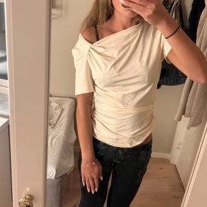  cremevit topp - Säljer denna jättesöta topp då den tyvärr är för stor för mig 💕Toppen har en asymmetrisk halsringning och sitter tight över kroppen. 