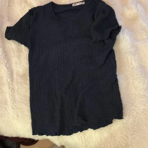 Mörkblå ribbad t-shirt från Zara - Snygg mörkblå t-shirt från Zara i storlek S. T-shirten har korta ärmar och är gjord i ett ribbat, krinklat material som ger en cool textur. Rund halsringning och enkel, rak passform. Perfekt för dig som gillar stilrena och bekväma plagg.