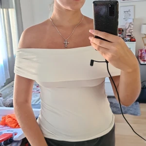 Vit offshoulder topp från New Yorker - Säljer en vit offshoulder topp från New yorker i storlek S. Toppen har en tight passform och är sydd i mjuk bomullsmix. Den har rynkade detaljer vid ärmarna och en bred kant över axlarna som ger en snygg och stilren look.