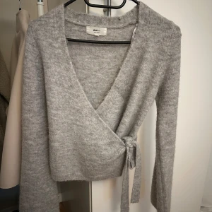 Grå omlottkofta från Gina Tricot - Supermjuk grå omlottkofta från Gina Tricot med knyt i sidan. Endast använd en gång så är som ny💕