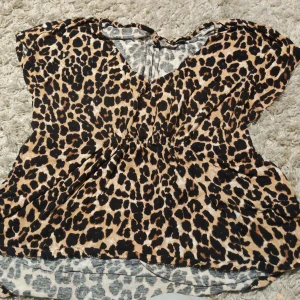 Leopardmönstrad blus från Gina Tricot - Säljer en snygg blus från Gina Tricot i storlek M med leopardmönster i svart och beige. Blusen har v-ringning, korta ärmar och ett lätt rynkat parti i midjan som ger en schysst siluett. Perfekt för dig som vill sticka ut med djurmönster!