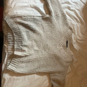 Beige stickad tröja med v-ringning - Supermysig beige stickad tröja från lager 157med v-ringad hals och grovstickat mönster. Tröjan har långa ärmar och breda ribbade muddar vid ärmslut och nederkant. Perfekt för lager-på-lager och chill höst- och vinterstil.