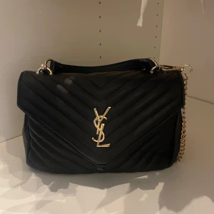 Svart quiltad YSL axelväska i skinn - Säljer min favorit väska som är en svart quiltad axelväska från YSL med ikoniskt guldigt YSL-emblem framtill. Självklart inte den riktiga ❤️skicka gärna vid frågor