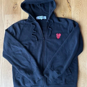 Svart Comme des Garçons Play Hoodie - Tjenare! Säljer en Svart hoodie från Comme des garçons. Säljer tyvärr denna tröjan som gett mig som mest komplimanger. Tröjan har lite mer lösare passform men sitter riktigt snyggt på. Perfekt för en hostigare dag och det kallare väder som ska komma! Vid frågor och funderingar är det bara att skriva! (OBS CDG Play sitter inte tts, dvs denna tröjan sitter mer som en M)