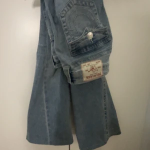 True Religion ljusblå bootcut jeans - Säljer ett par ikoniska ljusblå jeans från True Religion i joey modellen strl W26, har sytt upp dom så dom passar någon som är cirka 160cm säljer dom för dom är lite för stora för mig.
