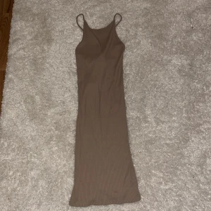 Beige ribbad klänning - Snygg beige ribbad klänning med smala axelband. Perfekt för en stilren look. Klänningen har en figurnära passform och är i en längre modell.