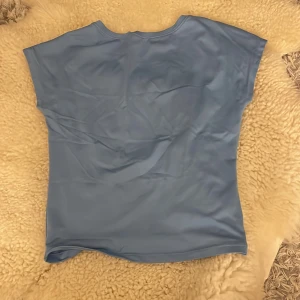 Blå kortärmad topp - Säljer en enkel och stilren blå topp med korta ärmar. Perfekt för en avslappnad look. Toppen är öppen i ryggen och rak i fram.