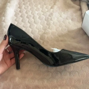 Svarta pumps med spetsig tå - Eleganta svarta pumps i lack med spetsig tå. Klackhöjden är 7cm