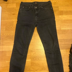 Svarta jeans från Lee - Snygga svarta jeans från Lee med en klassisk design. De har en knapp och dragkedja framtill samt fem fickor. Perfekta för en stilren look. W33 L33