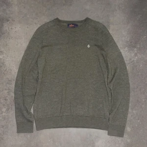 Grön tröja från Morris - Säljer en stilren grön tröja från Morris i 100% merinoull. Tröjan har en liten broderad detalj på bröstet och ribbade muddar vid ärmslut och nederkant. Perfekt för kyligare dagar! Inga defekter och är i 10/10 skick. Tröjan är i L barnstorlek vilket motsvarar xs i herrstorlek.