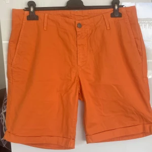 Orange shorts från italienska Colmar - Snygga orange shorts från Colmar i en klassisk design. De har en knapp och dragkedja framtill samt hällor för bälte. Perfekta för en färgglad och stilren look.