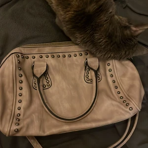 Beige axelväska med nitar - Snygg beige axelväska med coola nitar och dragkedja. Perfekt för att ge din outfit en edgy touch. Väskan har praktiska fack inuti för enkel organisering.