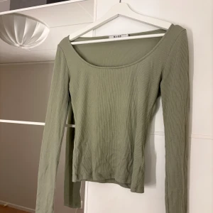 Grön ribbad topp från NA-KD - Snygg grön ribbad topp från NA-KD med långa ärmar och en stilren design. Hör av er vid funderingar eller om ni vill ha bilder med hur plagget sitter på mig. Titta gärna in mina andra plagg!