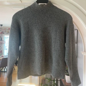 Grå stickad polotröja - Stilren grå stickad polotröja med ribbade detaljer vid krage, ärmslut och nederkant. Stl. XS!