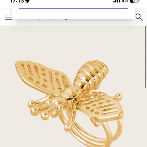 Guldfärgad ring med insektmotiv LETAR - Unik guldfärgad ring med ett detaljerat insektmotiv. Ringen har en intrikat design med vingar och kropp som ger ett elegant och iögonfallande utseende. Perfekt för att lägga till en touch av naturinspirerad stil till din look.