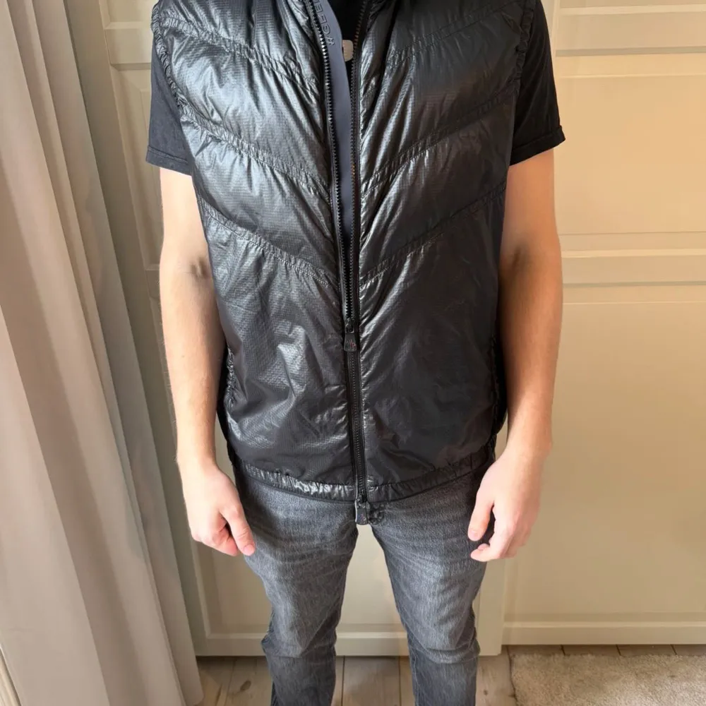 Snygg svart quiltad väst med dragkedja framtill. Perfekt för lager-på-lager och ger en stilren look. Västen har en modern design med tryck på kragen och ryggen. Pris kan diskuteras vid snabb affär. Storlek L men passar bra för dom med storlek M också.. Takit.