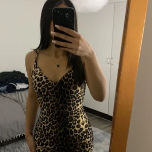 Leopardmönstrad klänning från Lovers - Snygg leopardmönstrad klänning från Lovers med smala axelband och en figurnära passform. Perfekt för att sticka ut med ett djärvt mönster. Klänningen har en v-ringad design som ger en elegant touch.