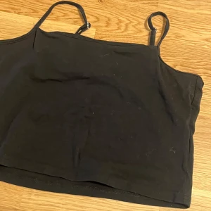 Svart linnetopp från 157 - Säljer en enkel och stilren svart linnetopp från 157. Toppen är tillverkad i mjuk bomull med en liten andel elastan för extra komfort. Perfekt för varma dagar eller som lager under andra plagg.