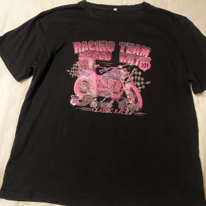 Svart t-shirt med tryck - Säljer en svart t-shirt med rosa tryck, i storlek M. Kontakta mig om du har frågor!