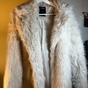Vit pälsjacka  - Säljer en fluffig och stilren vit pälsjacka. Jackan har en klassisk design med långa ärmar och är perfekt för att hålla dig varm och trendig. Passar utmärkt för vår dagar.