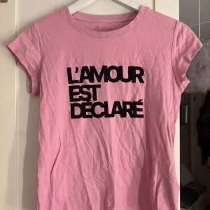 Rosa t-shirt från Zadig & Voltaire - Snygg rosa t-shirt från Zadig & Voltaire med texten 'L'AMOUR EST DÉCLARÉ' i svart på framsidan. Den är kortärmad och tillverkad i mjukt bomullsmaterial. Perfekt för en avslappnad stil.