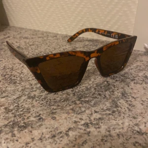 Leopardmönstrade solglasögon från Even&Odd - Snygga solglasögon med leopardmönster från Even&Odd. De har en trendig, kantig form och mörka linser som ger ett coolt uttryck. Perfekta för att ge din outfit en extra touch av stil.