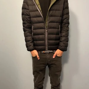 Svart dunjacka från Colmar - Säljer en svart dunjacka från Colmar med huva och dragkedja. Jackan har en quiltad design och långa ärmar. Perfekt för kyliga dagar med sin stilrena look och varma material.