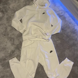 Nike sett ( går att köpa var o sig) - Säljer en vit hoodie och matchande byxor från Nike. Hoodien har en klassisk design med känguruficka och Nike-logga på bröstet. Byxorna har en bekväm passform med resår i midjan och Nike-logga på benet. Perfekt för en avslappnad stil.