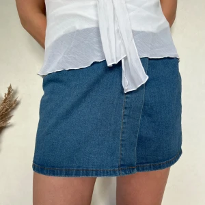 Blå jeanskjol - Säljer en klassisk blå jeanskjol i kort modell. Kjolen har enkel design med synliga sömmar och hög midja. Perfekt att matcha med en enkel topp eller hoodie.