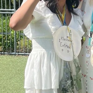 Vit volangklänning med puffärm - Säljer en söt vit klänning med volanger och puffärmar. Klänningen har en markerad midja och dubbla lager i kjolen för extra volym. Perfekt för somriga tillfällen och studentfirande. Skriv för fler bilder!!! 