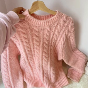 Rosa stickad tröja från Le Vrai - Mysig rosa stickad tröja från Le Vrai med flätstickat mönster och rund halsringning. Tröjan har långa ärmar och ribbade muddar vid ärmslut och nederkant. Perfekt en sommarkväll!