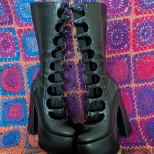 Svarta platåstövlar med spännen - Höga svarta platåstövlar/boots med rejäl platå och klack i storlek 38. Skorna har flera spännen framtill men oroa dig inte, det finns dragkedja på sidan. Använda endast innomhus ett fåtal gånger för att leva min badass bitch fantasi ( Att gå fram och tillbaka i vardagsrummet ) Hoppas jag kan hitta ett hem till dem hos en äkta badass, kanske det är du?   Jag kan mötas i Göteborg/kungälv-området men är du längre bort kan vi säkert lösa det på något vis bara att fråga!