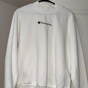 Vit sweatshirt från Champion - Säljer en klassisk vit sweatshirt från Champion med broderad logga på bröstet. Tröjan har rund halsringning och långa ärmar. Perfekt för en clean och sportig stil. Använd endast 1 gång. Riktigt bra skick. 
