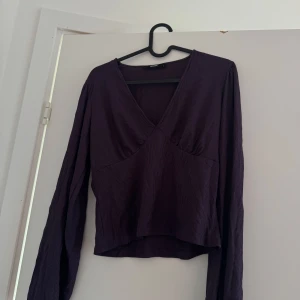 Långärmad v-ringad lila blus - Fin lila, v-ringad blus med ballongärmar. Ribbat material som sitter superfint mot kroppen. Strl L och normal i storleken, sparsamt använd. Säljes då den tyvärr inte kommer till användning längre <33
