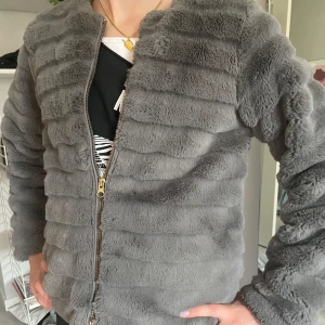 Grå pälsjacka - Mysig grå pälsjacka med guldig dragkedja.