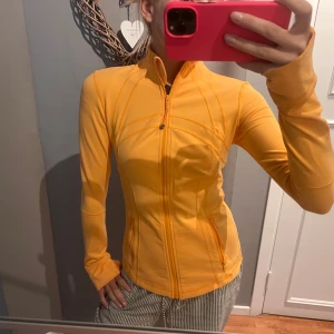 Orange träningsjacka från lululemon - Lululemon tränings jacka/tröja i orange , super skön och passar allt från XS-M