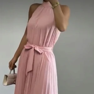 Ljusrosa långklänning med knytband - Nyköpt elegant ljusrosa långklänning med hög hals och med ett löst knytband i midjan. Klänningen har ett mjukt, fallande tyg och är ärmlös. I storlek M men passar även storlek S